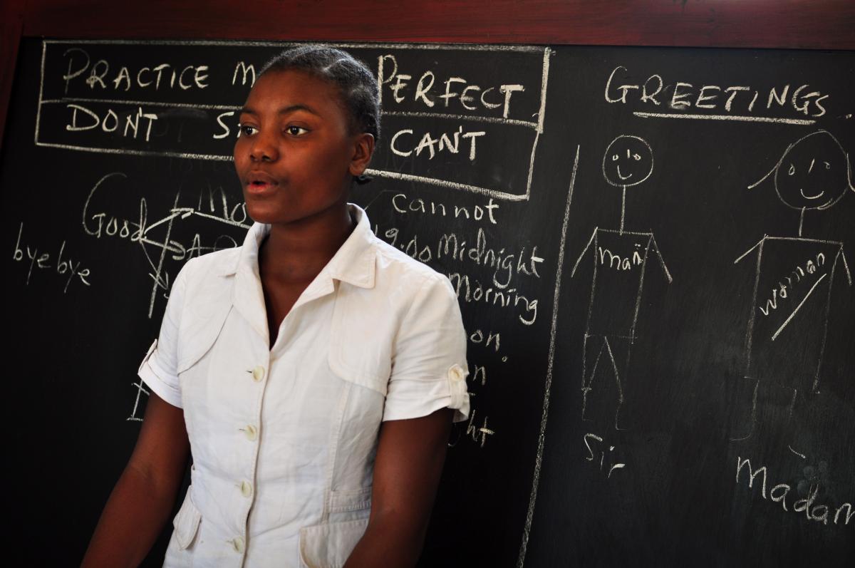 A young mother stands at the blackboard at school