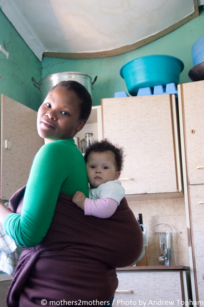 Mother holds her baby on her back