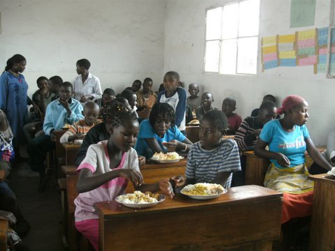 Congolese students eating a meal cooked for them after school