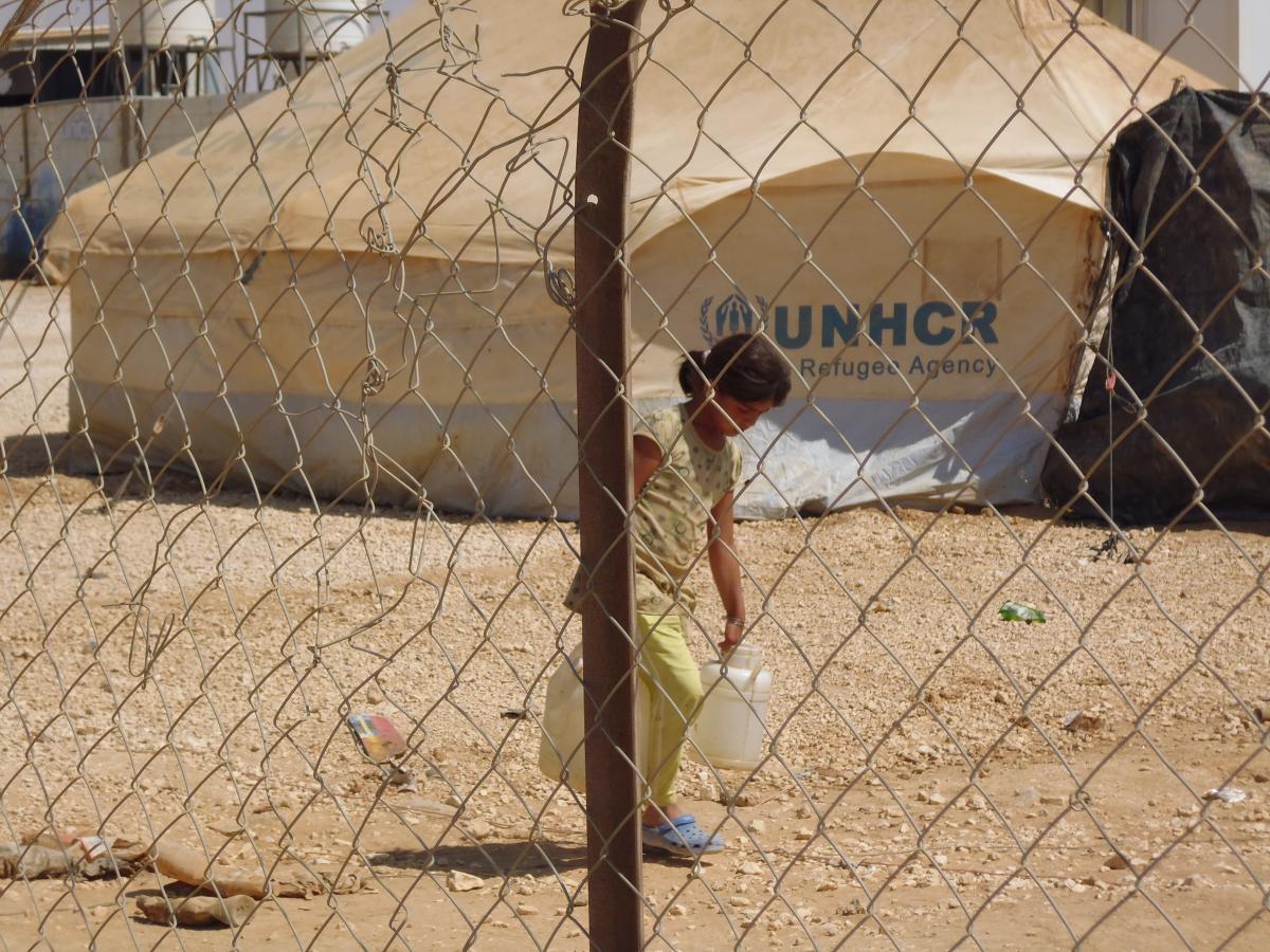 A little girl doing her water chore in a Syrian refugee camp